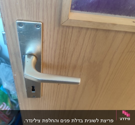 ידית דלת מתכת על דלת עץ